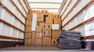 Interior of a moving truck filled with stacked cardboard boxes and folded blankets.
