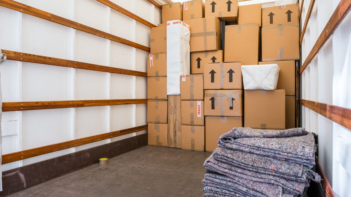 Interior of a moving truck filled with stacked boxes and moving blankets.