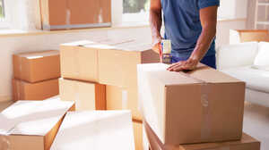 A person is packing boxes in a bright room with several cardboard boxes around.