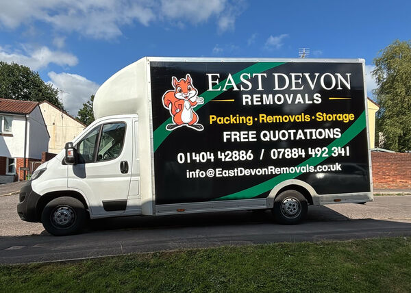 White removal truck with "East Devon Removals" branding parked on a residential street.