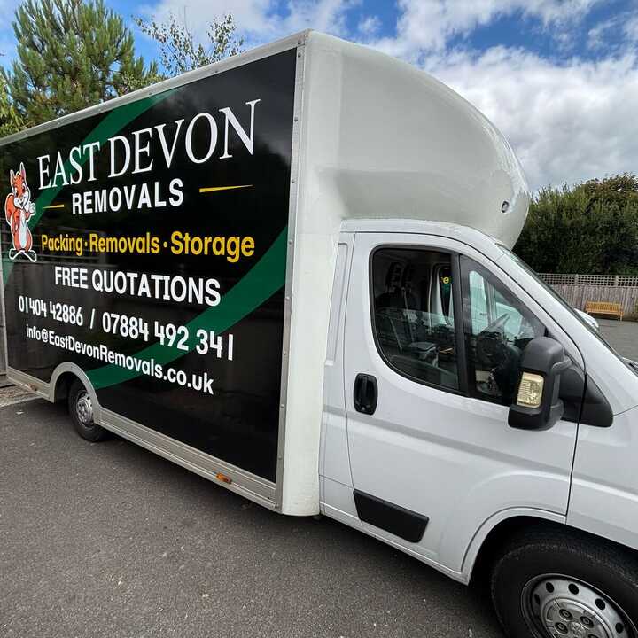 East Devon removals truck parked, featuring bold black signage and contact information.
