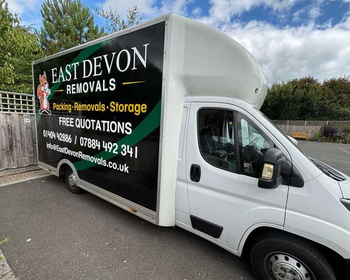A removal truck with "East Devon Removals" branding parked on a residential street.