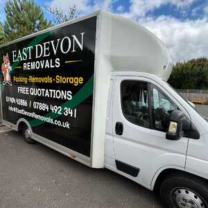 East Devon removals truck parked, featuring bold black signage and contact information.