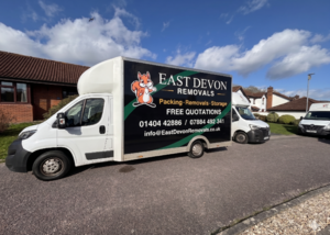 White removal truck with "East Devon Removals" branding parked on a residential street.