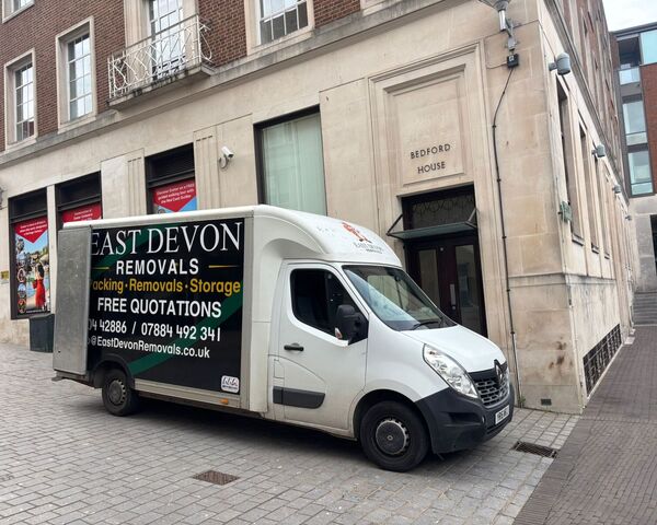 East Devon Removals van parked on a cobbled street in Exeter city centre, showing the van's side panel with contact details
