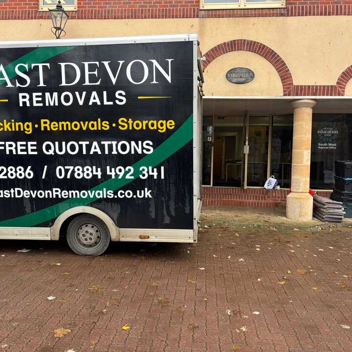 A removal truck parked outside a building with signage for East Devon Removals.