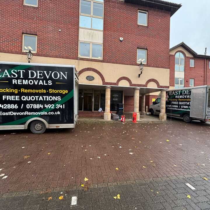 A removal truck parked outside a brick building on a rainy day.