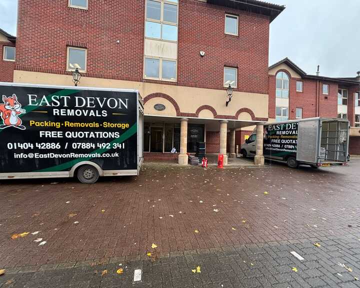 Person loading boxes into a truck on a street with houses in the background.