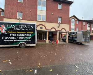 Person loading boxes into a truck on a street with houses in the background.