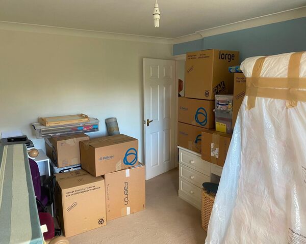 Bedroom packed with cardboard boxes and a wrapped wardrobe box during a house move from Exeter to Cranbrook