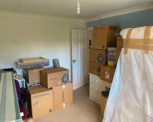 Bedroom packed with cardboard boxes and a wrapped wardrobe box during a house move from Exeter to Cranbrook
