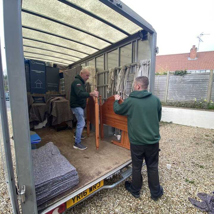 Two men are loading furniture into a truck in a residential area.