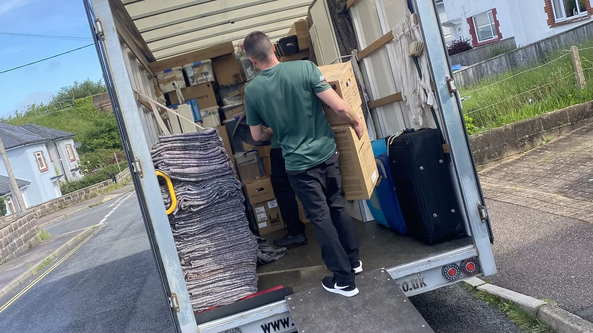 A person loading boxes into a moving truck on a driveway.