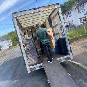 Person loading boxes into a truck on a street with houses in the background.