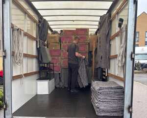 Removal team member packing boxes and household items into the back of an East Devon Removals van during the Exeter house move