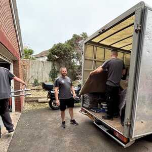 Two men are moving a large cardboard box from a vehicle.